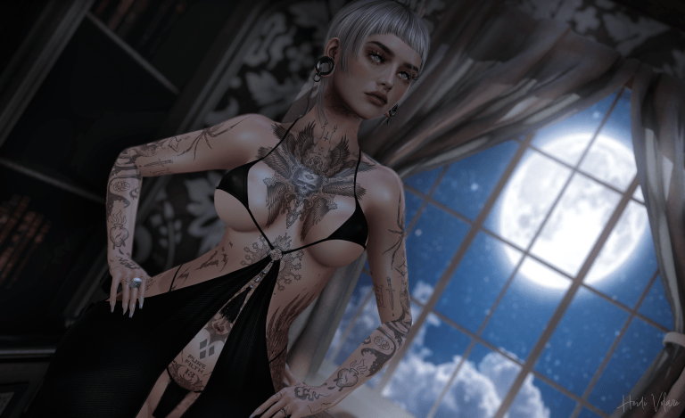 A tattooed woman with short silver hair poses in a flowing black dress before a large moonlit window, surrounded by soft shadows and a dreamy midnight atmosphere.